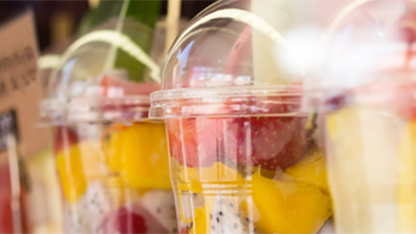 Una serie de recipientes de plástico para alimentos, llenos de rodajas de fruta de colores.