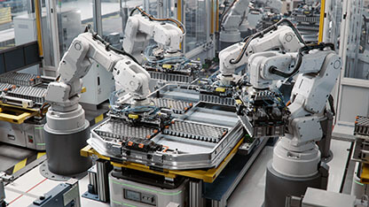 Industrial Robot Arms Assemble Lithium-Ion EV Battery Pack. Row of White Robotic Arms at Automated Production Line at Bright Modern Factory. Electric Car Manufacturing Inside Automotive Smart Factory 